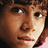 Pixelated close-up of a person's face with brown hair, dark eyes, and a neutral expression against a dark background.