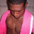 Pixelated image of a person with dark hair wearing a pink jacket and dark necklace, head slightly bowed, against a gray background.