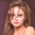 Pixelated close-up of a person with light brown hair, fair skin, and a neutral expression against a dark purple background.
