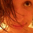Pixelated close-up of a face with orange skin tones, dark brown hair, and two bright circular light sources on the lower left and right edges.