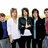 Group of five people standing side-by-side with a black background and white '<33' symbol on the right.