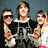 Three pixelated figures stand side-by-side against a dark blue background, with the central figure wearing a black hoodie with white text.