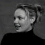 Four grayscale show a person in a black turtleneck with hair in a bun, displaying sequential facial expressions and head positions