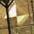 A static pixelated image shows a dark vertical structure with a curved top against a light brown background with two bright white rectangular shapes.