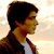 Pixelated profile of a person with dark hair wearing a dark jacket over a light shirt against a light gradient background.