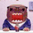 Pixelated cartoon character with brown skin, red mouth, and blue suit sitting at a desk.