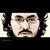 Pixelated static image of a human face with neutral expression, dark eyebrows, and mustache against black background.