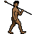 Pixelated figure with brown skin and black hair holding a zigzag staff, standing in profile against gray background.