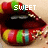 Pixelated lips with colorful candy-like patterns and the word 'SWEET' overlaid in white block letters.