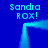Blue background with four instances of 'Sandra ROX!' text in cyan pixelated font, each positioned around a glowing cyan rectangular frame.
