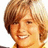Pixelated close-up of a smiling person with light brown hair, wearing a yellow garment against a white background.