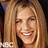 Pixelated close-up of a smiling person with long light brown hair, visible teeth, and a dark background with partial white text.