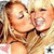 Two blonde women in close embrace, one kissing the other's cheek while both smile broadly.