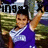 Pixelated image of a person in a blue and white outfit with one arm raised, standing before a blurred background with visible text elements.
