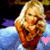 Pixelated image of a blonde woman in red clothing with arms crossed, standing against a blue and purple background featuring a pink heart symbol.