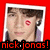 Pixelated portrait of a person with brown hair and a red lip mark on the cheek, framed by white border on red background, with red text 'nick.jonas!' at bottom.