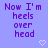 Pixelated purple text on light blue background with two white heart icons, displaying the phrase 'Now I'm heels over head' in a static layout.