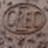 A low-resolution static icon with indistinct brown and gray tones forming a circular shape on a pixelated background.