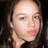 Pixelated close-up of a person with light skin, dark hair, and pink lips resting hand on chin against dark background.