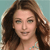 A pixelated close-up of a person with long brown hair against a light blue background, wearing a light blue strap visible on the shoulder.