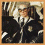 A pixelated image of a person with light-colored hair and glasses, wearing dark clothing against a blurred background.