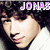 Pixelated close-up of a person with dark hair and light skin, wearing white clothing, with purple text above the head.
