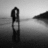 Black-and-white pixelated image of two figures embracing on a beach with text overlay reading "fall into summer love" in pixelated font.