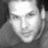Grayscale pixelated image of a person's face with visible eyes, nose, mouth, and partial hair against dark background.