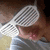 A pixelated image of a person wearing a white mesh headpiece with visible lines, partially obscured by the headpiece