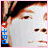 Pixelated close-up of a person's face with dark hair, featuring red heart and blue text symbols on the left edge.