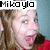 Pixelated image of a person with light skin and blue eyes, wearing red clothing, under a white banner reading 'Mikoylo' in black block letters.