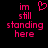 Pixelated pink text on black background reads "im still standing here" with a heart symbol above the text on the left side.