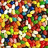 A dense, pixelated collage of multicolored shapes and patterns with no discernible figures or text, set against a black and gray background.