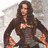 A static image of a woman with long brown hair in a dark dress, standing against a light background with arms akimbo.