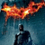 Batman silhouette stands beneath a fiery bat symbol against dark blue background with subtle smoke effects.