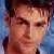 A pixelated close-up of a person's face with brown hair, visible eyes and nose against a blue background.
