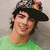 A person in a green shirt and patterned cap smiles against a light gray background, with subtle variations across four views.
