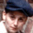 Pixelated close-up of a person wearing a dark blue cap with a black brim, light skin tone, and visible facial features including eyes, nose, and mouth.