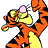 Pixelated orange tiger character with black stripes and yellow belly holds pink object, set against orange background with white text reading "GUESS WHAT THAT SPELLS" and "THAT SPELLS TIGGER!".