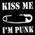 Black background with white text 'KISS ME I'M PUNK' and a safety pin graphic, next to a blue skull-and-crossbones symbol on white.