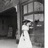 Black-and-white pixelated image of a person in a white dress standing in a doorway with dark interior and light exterior spaces.