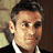 Static 48x48 pixel icon showing a close-up of a man's face with dark hair, light skin tone, and formal attire against a blurred background.
