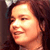 Pixelated close-up of a person's face with dark hair, warm lighting, and a neutral expression against a dark background.