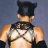 Pixelated static image of a character wearing a black mask and harness over a bare torso against a gray background.