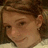 Pixelated close-up of a person's face with brown hair, visible ear, and light skin tone, cropped to show only the upper head and shoulders.