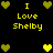 Pixelated yellow text "I Love Shelby" surrounded by green and yellow heart icons on a black background.