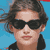 Static pixelated icon of a person with dark hair and sunglasses against a blue background, wearing a black top.