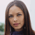 Pixelated close-up of a person with long brown hair, light skin, and closed eyes, wearing a dark blue top against a blurred background.