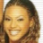 Pixelated close-up of a smiling person with brown hair against a light background, rendered in warm tones at 256x256 resolution.