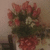 A bouquet of pink and white flowers with green foliage in a red-patterned vase on a light surface.